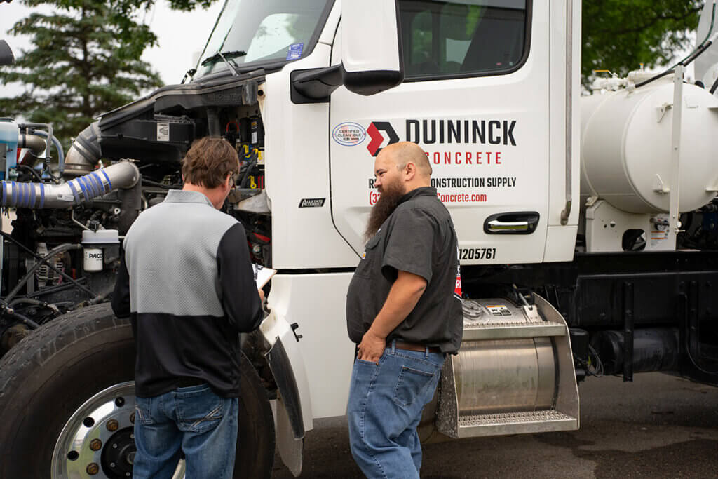 Two employees talking in front of mixer truck
